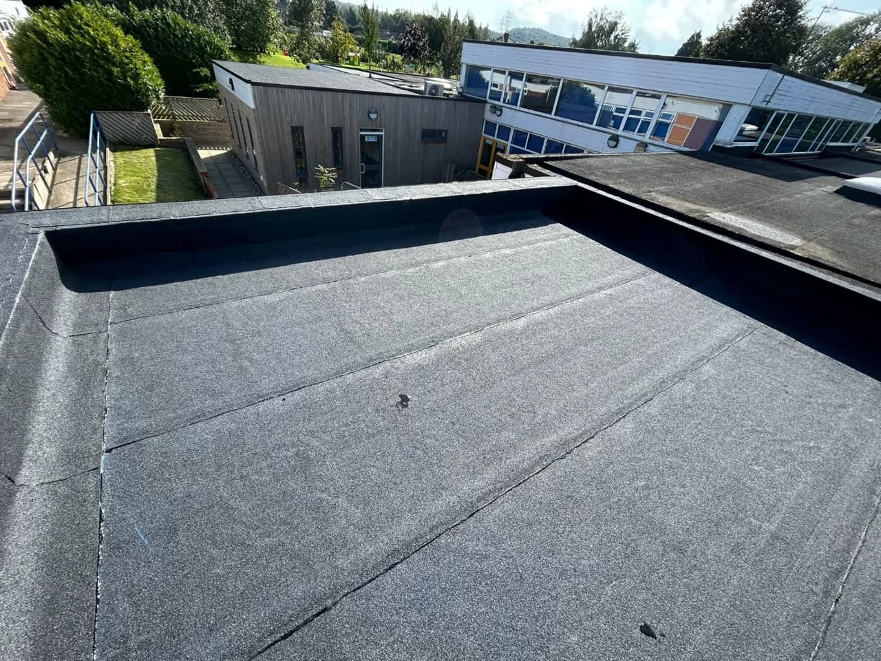 Completed built-up warm flat roof on the Normanby Primary School extension, with the existing school building behind.