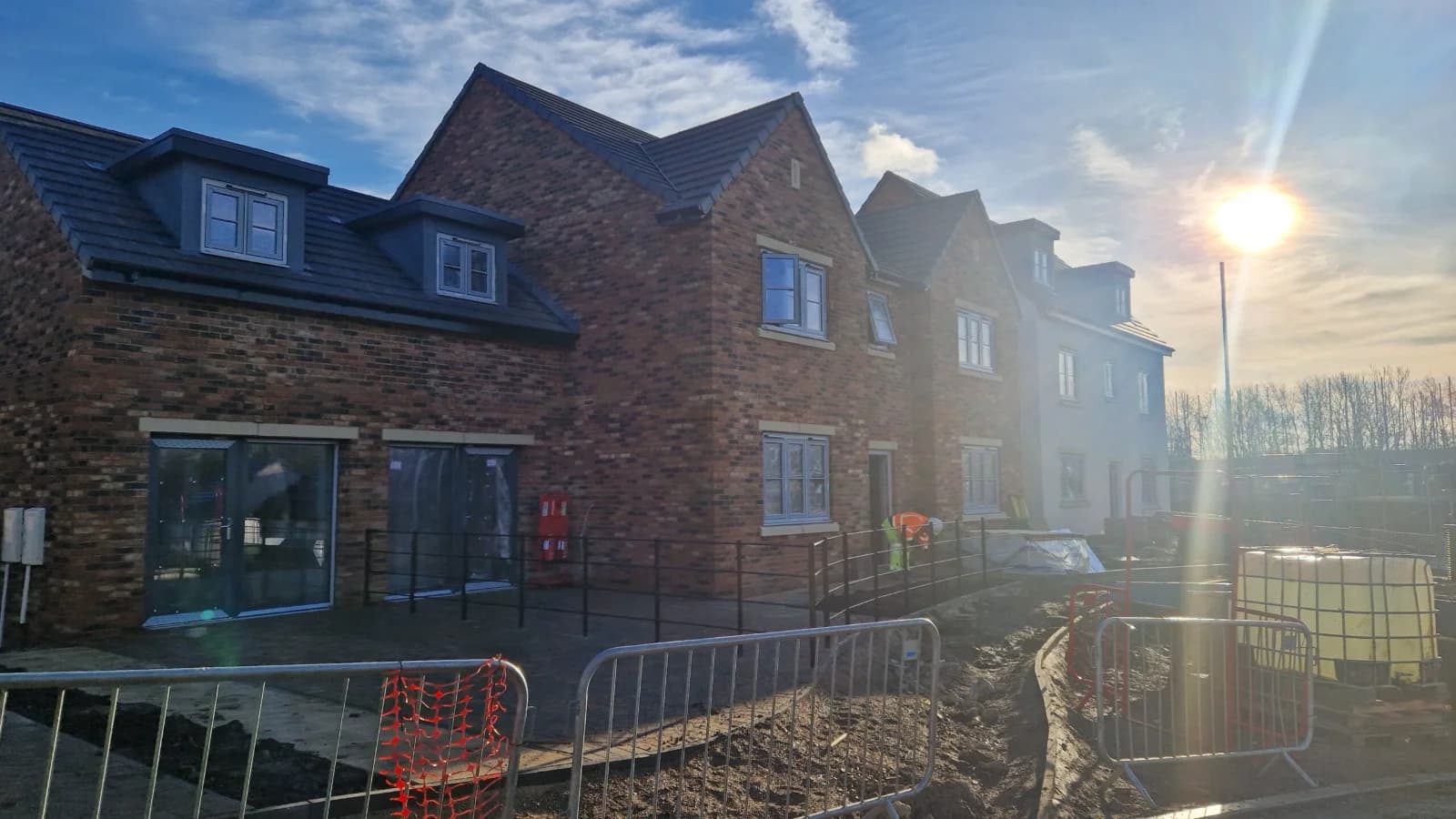 Completed new-build housing development at golden hour, dark tile pitched roofs against blue sky — commercial roofing contractor Northeast England